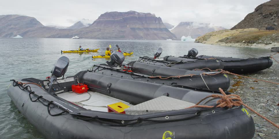 Kayaks row past parked rafts