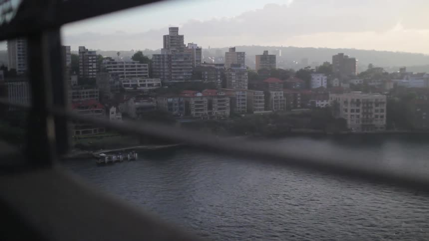 A first person view of water as they cross a bridge towards a city