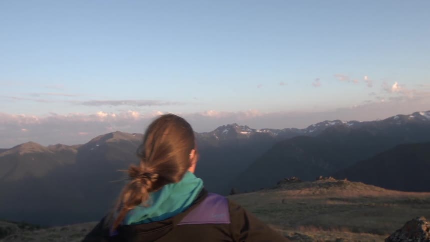 A woman looks out over a mountain range