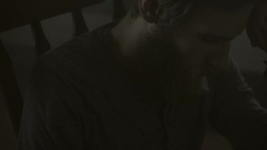 A man sitting in a dark room and looking down