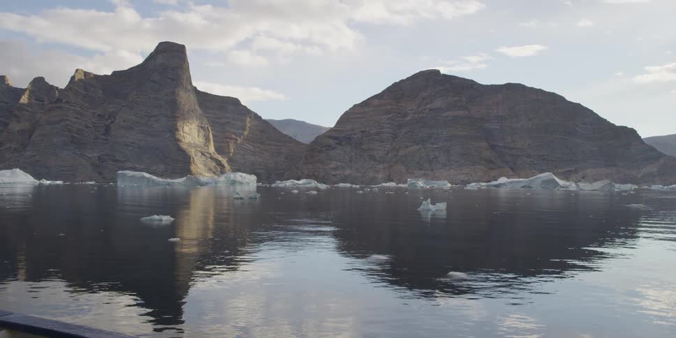 Ice in the water floats past a mountain