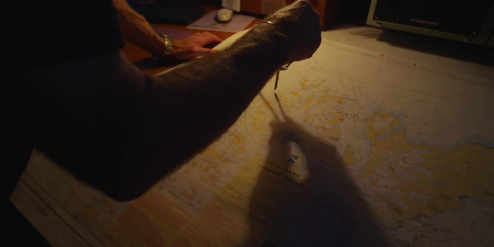 A man uses a metal compass on a map