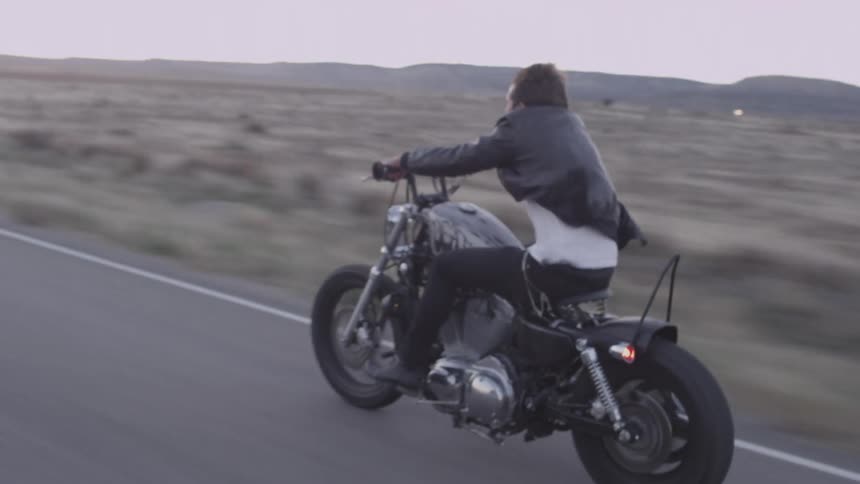 A man rides a motorcycle without a helmet