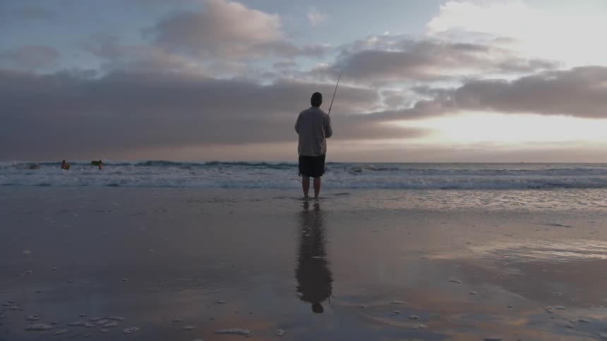 A man fishes from the beach