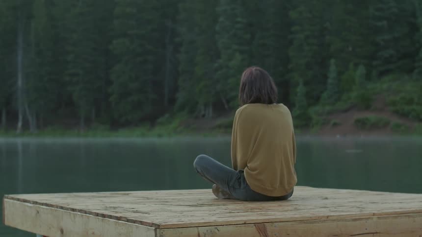 A person sits cross-legged on a dock