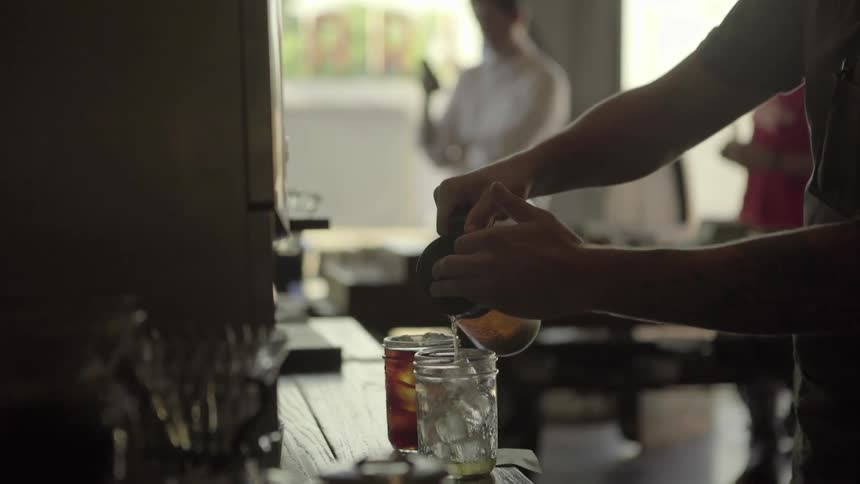 A man pouring a drink over ice in a cafe