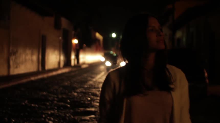 A woman walks down a dark road