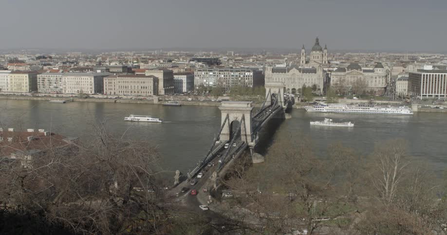 Ships float down a river with a city in the background