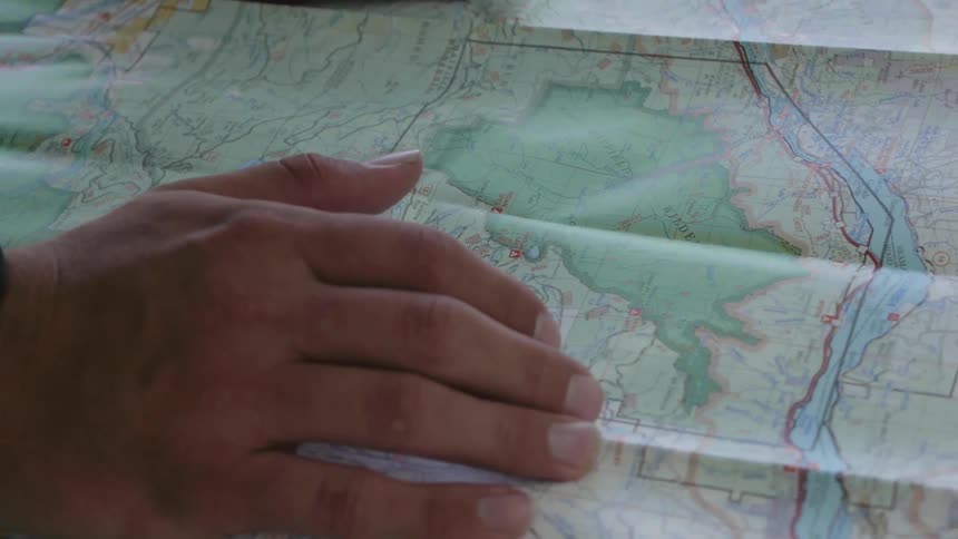 A person looks and points at places on a map