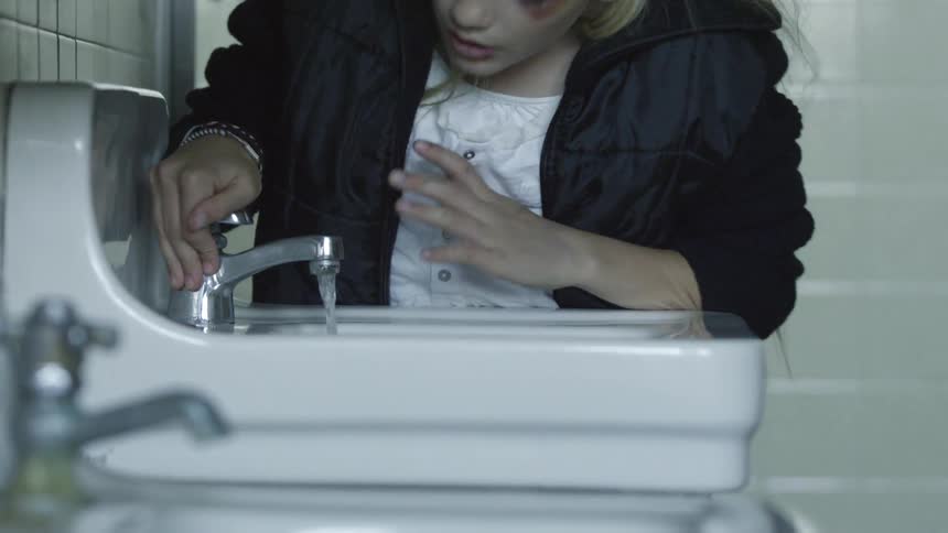 Girl taking a drink out of the bathroom faucet