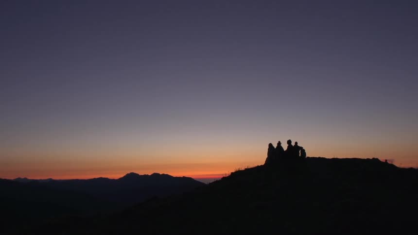 Five people standing on a hill at sunset