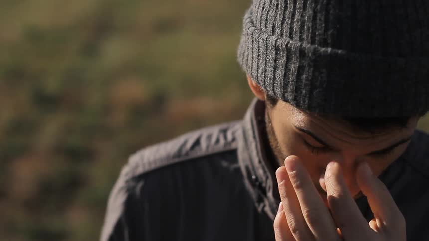 A young man touches his face