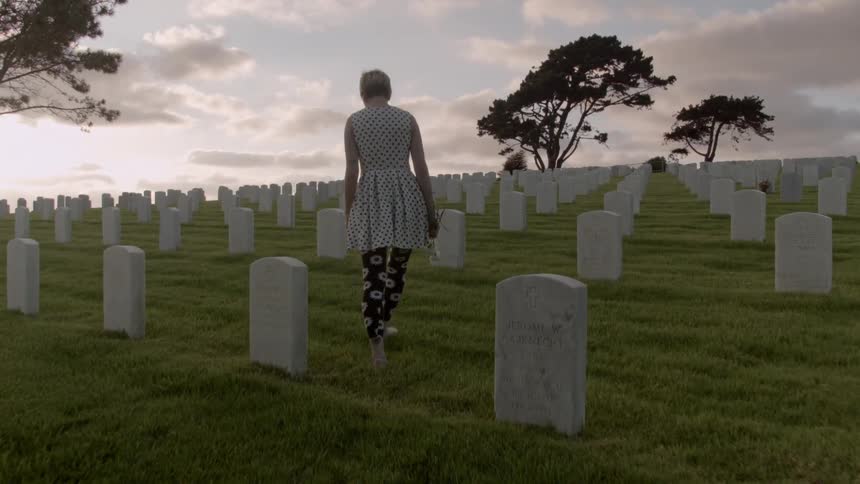 A woman walks through a graveyard