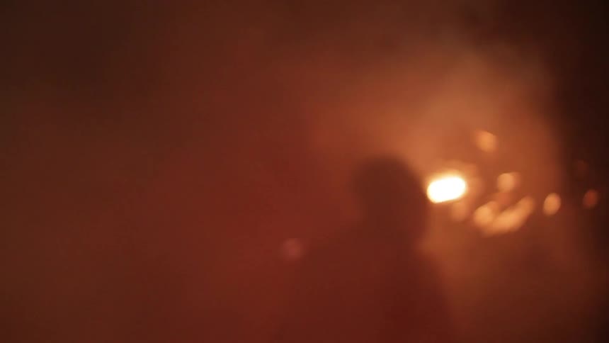 People dancing and swinging smoking sparklers at night time