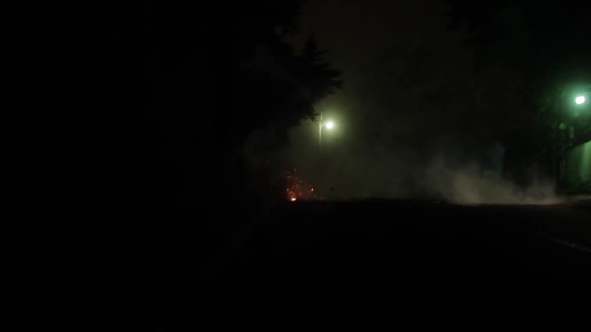 A person lights firecrackers on the streets of a neighborhood at night