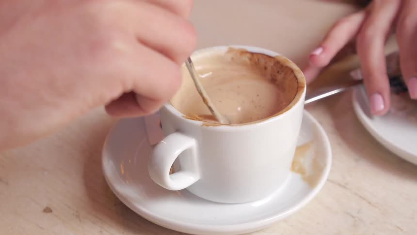 Someone stirring a frothy drink