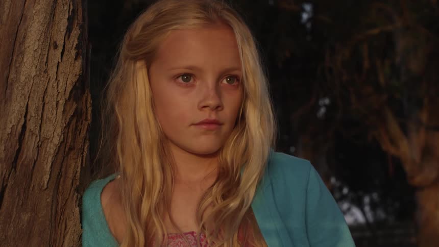 Blonde girl leaning on a tree