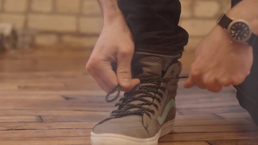 A man tying his shoes on a wooden floor