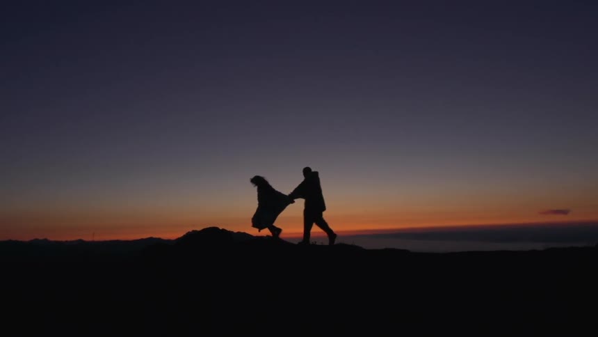 A couple running past a sunset