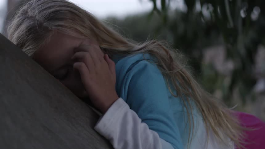 A young girl laying on a stump