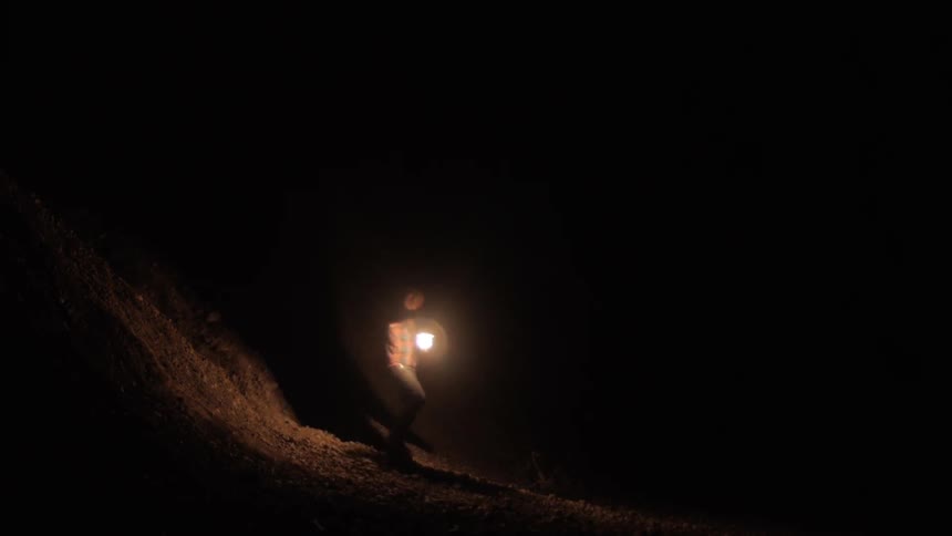 A person carrying a lantern walks into a dark cave