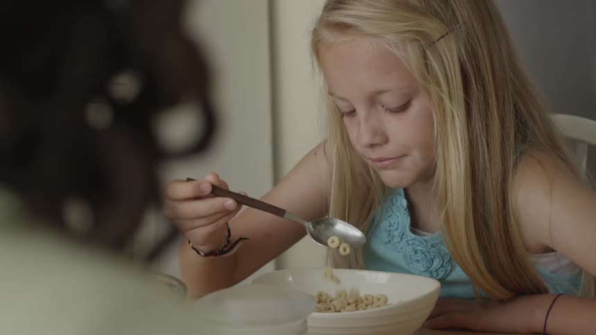 A little blonde girl eating cheerios