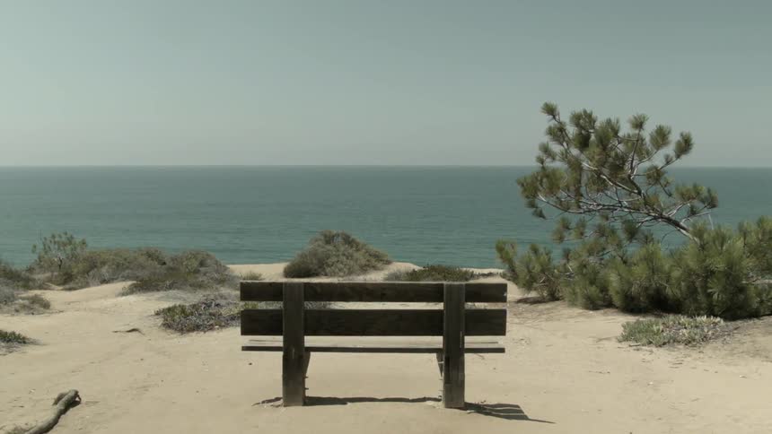 A wooden bench on a sandy beach