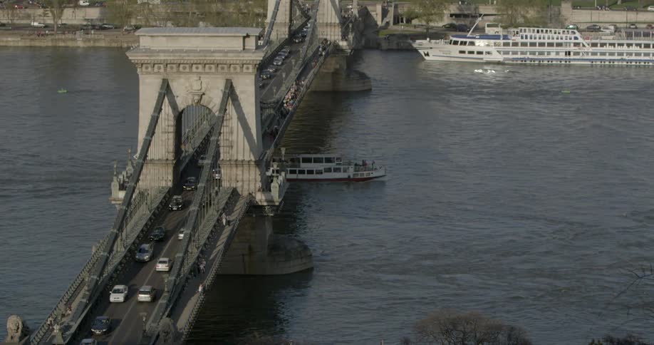 Boat floating underneath a busy bridge