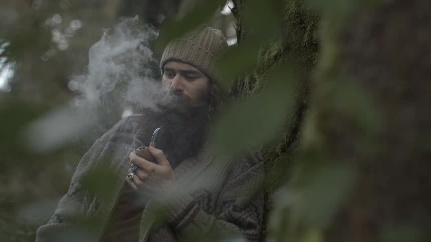 Man smokes his pipe in the forest