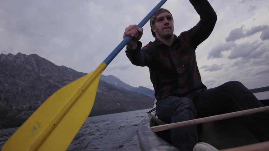 Man rows in water against cloudy sky