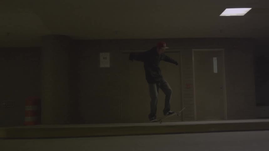 A young man skateboarding inside of a vacant parking garage