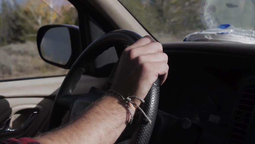 Man driving a car with one hand