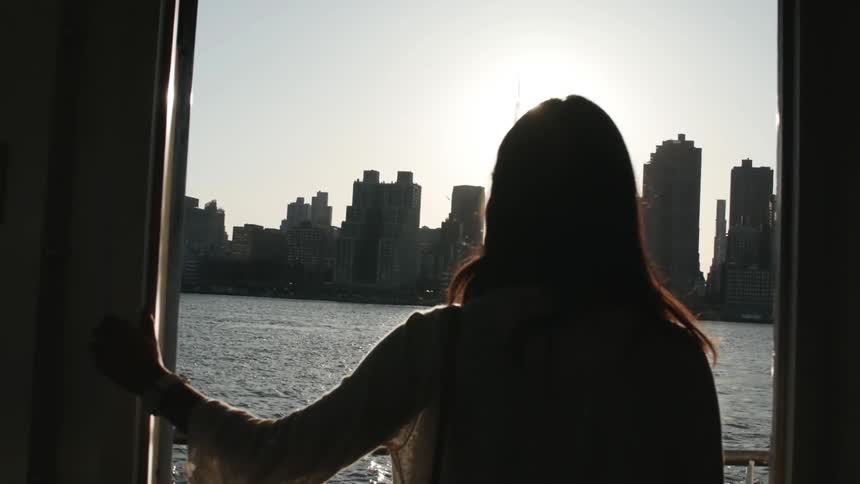 Woman wearing sunglasses looks at city skyline from a yatch