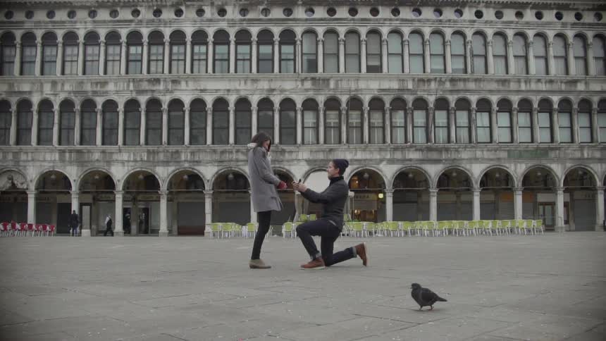 A man proposes marriage in front of a city building