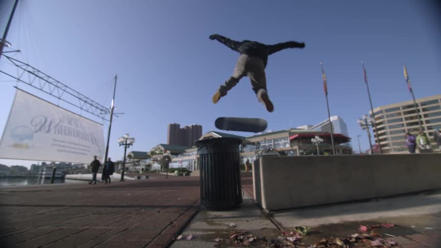 A skateboarder jumps over a trash can