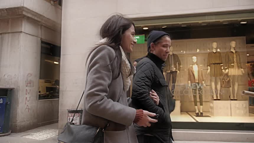 A couple walking down a busy sidewalk talking
