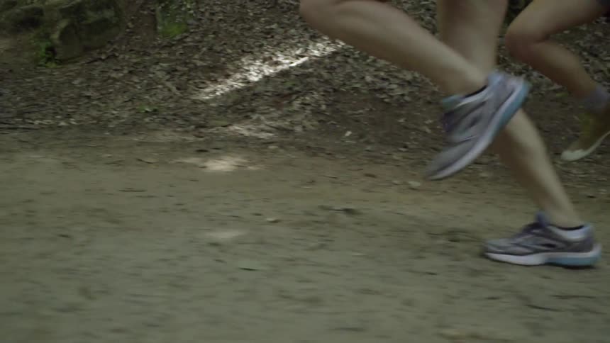 Two joggers run along a dirt path