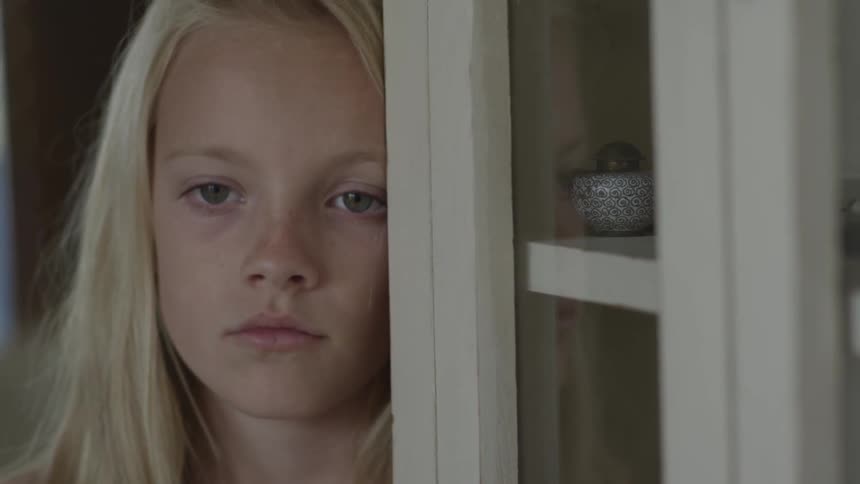 A young girl leans against the wall while lost in thought