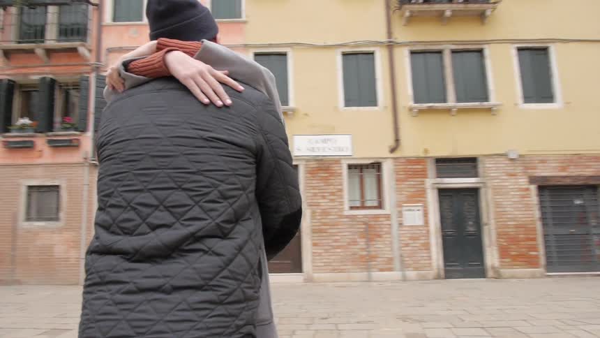 A man and woman hug and kiss in an urban area
