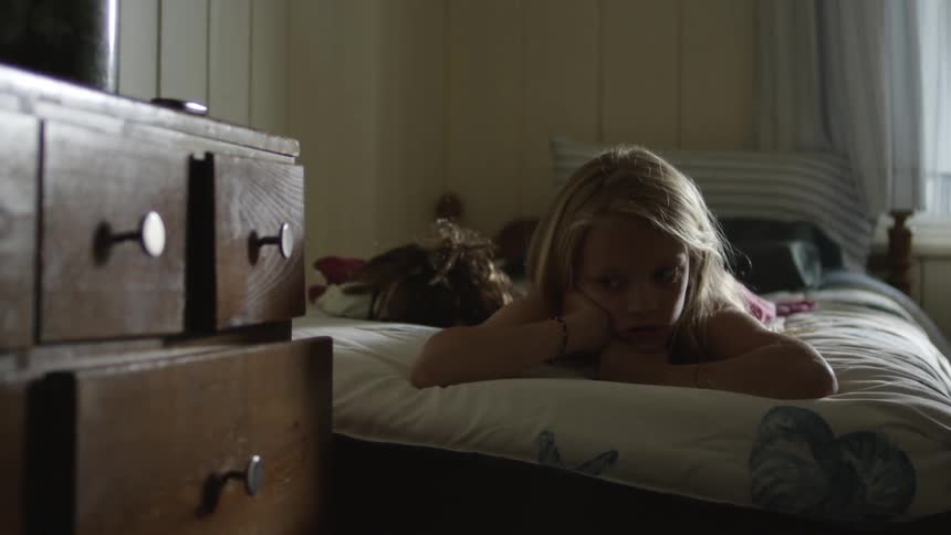 A young girl lies on a bed