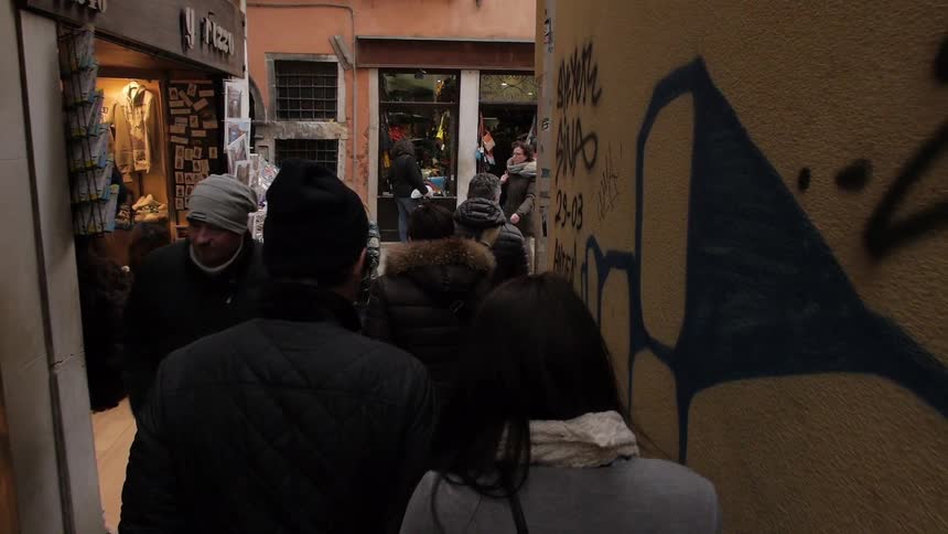 People walking down an alley towards shops on a sunny day