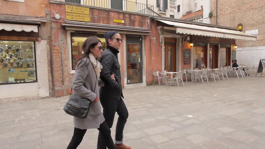 A couple walking past stores and a cafe