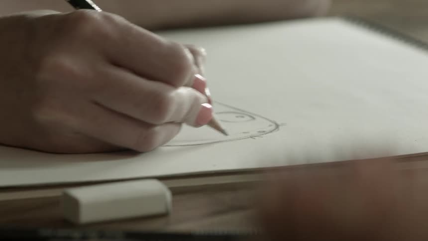 Person drawing on paper with a pencil