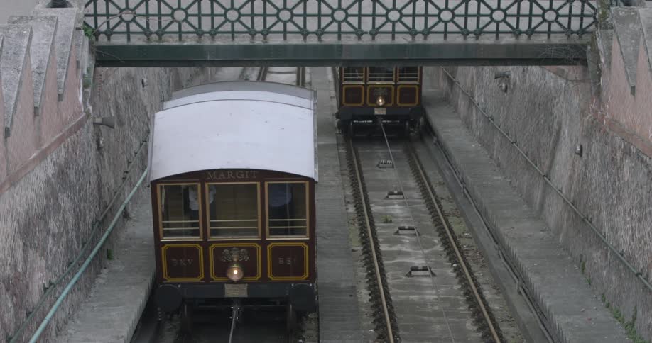 Two trolleys, going in opposite directions, pass under a bridge