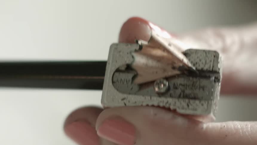 Person sharpening a pencil in a metallic sharpener