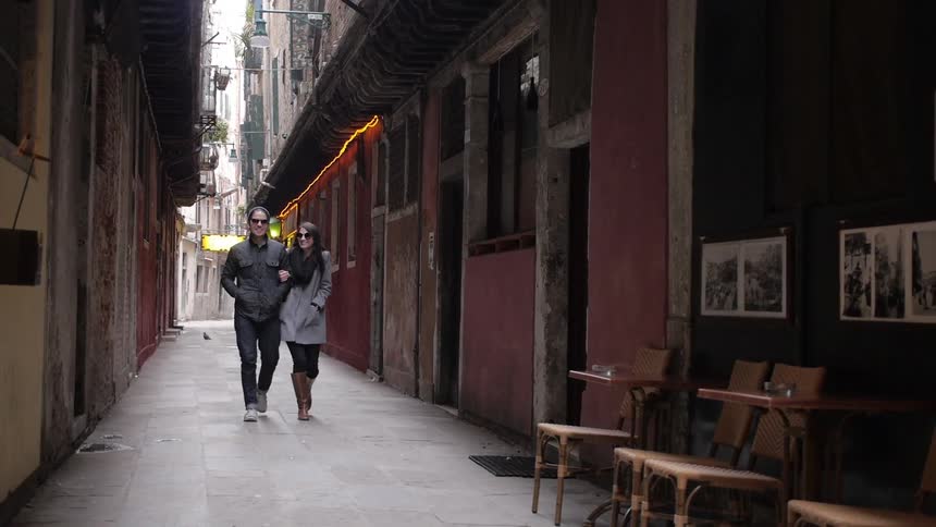 A man and a woman walk down an alleyway