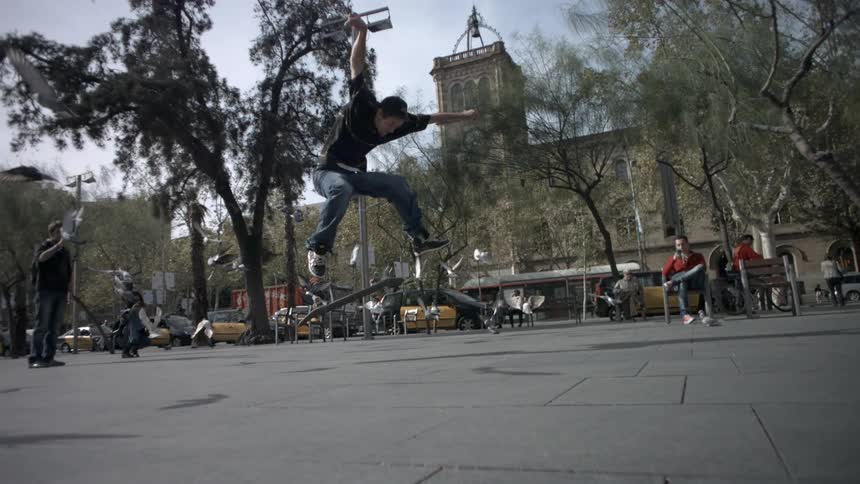 Birds fly away from a skateboarder's trick in a city park