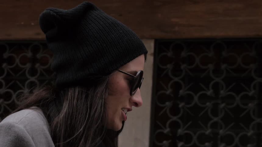 Woman walks down street with sunglasses on