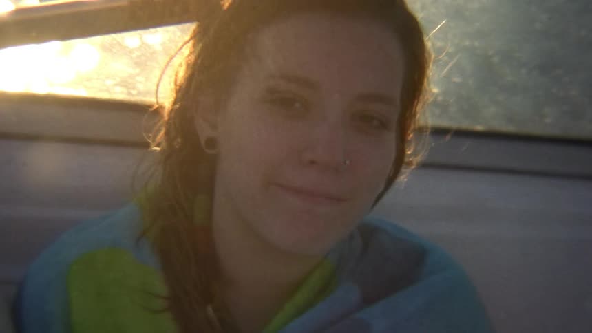 Woman wrapped in a towel sitting in a small boat on the water