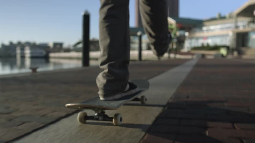 Young man skates in a skateboard on city streets next to river